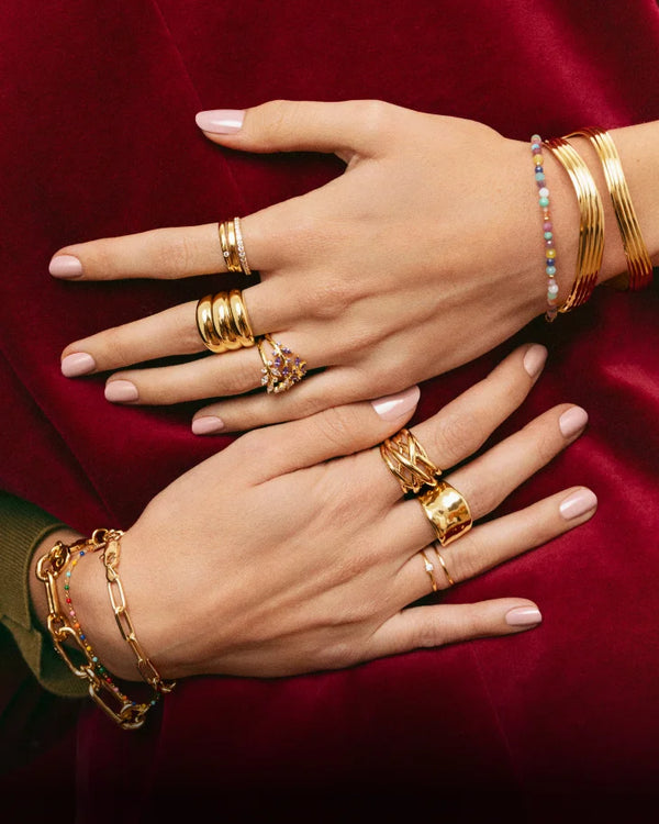 Dos manos con varios anillos y pulseras de oro cada una