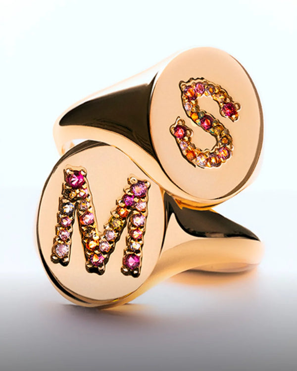 Dos anillos tipo sello de oro, uno de ellos con una M y otro con una S tallados con piedras de colores