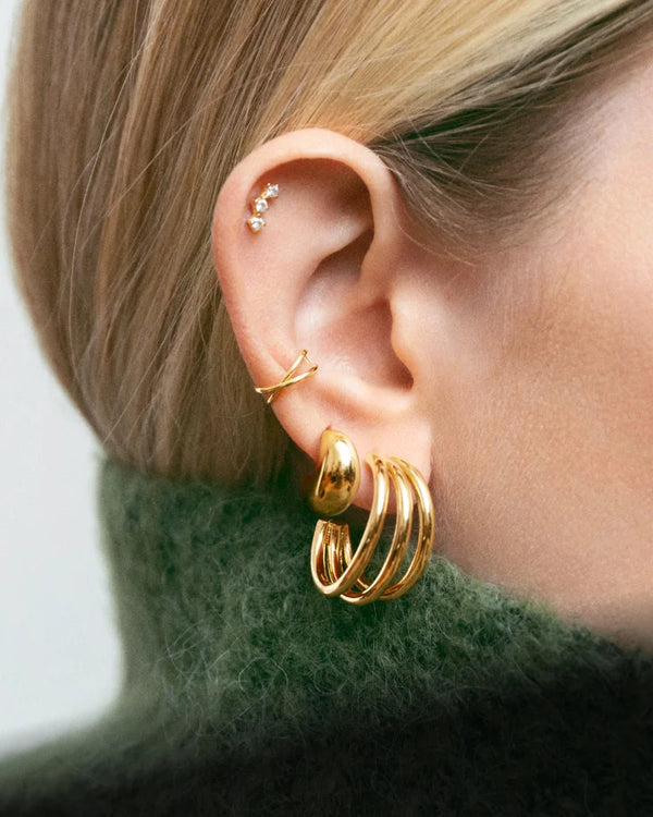 Una oreja de mujer con varios pendientes de oro